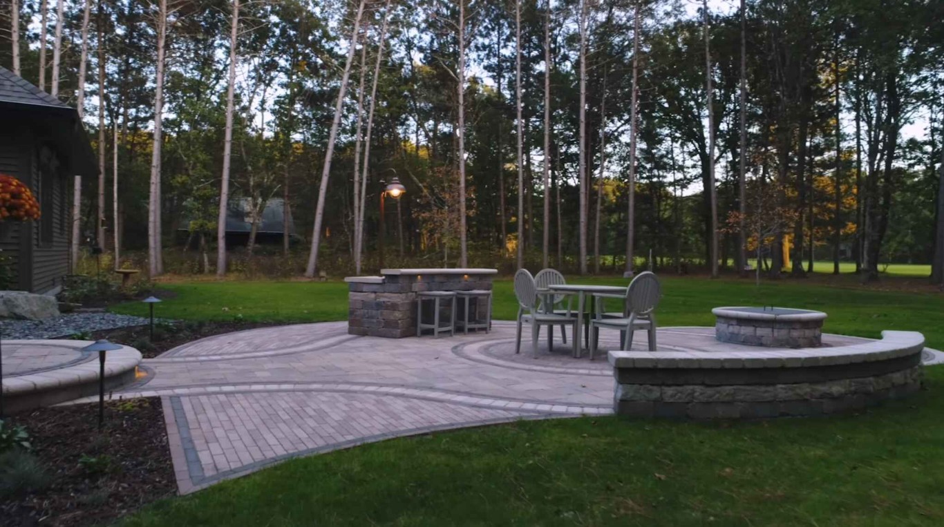 Hardscaped patio with pavers, outdoor furniture, and landscape lighting
